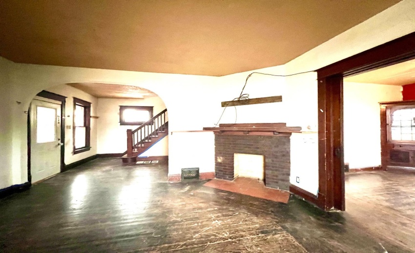 Living room leads to dining area. Original fireplace and woodwork.